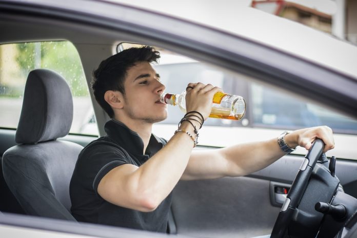 мужчина пьет алкоголь за рулем